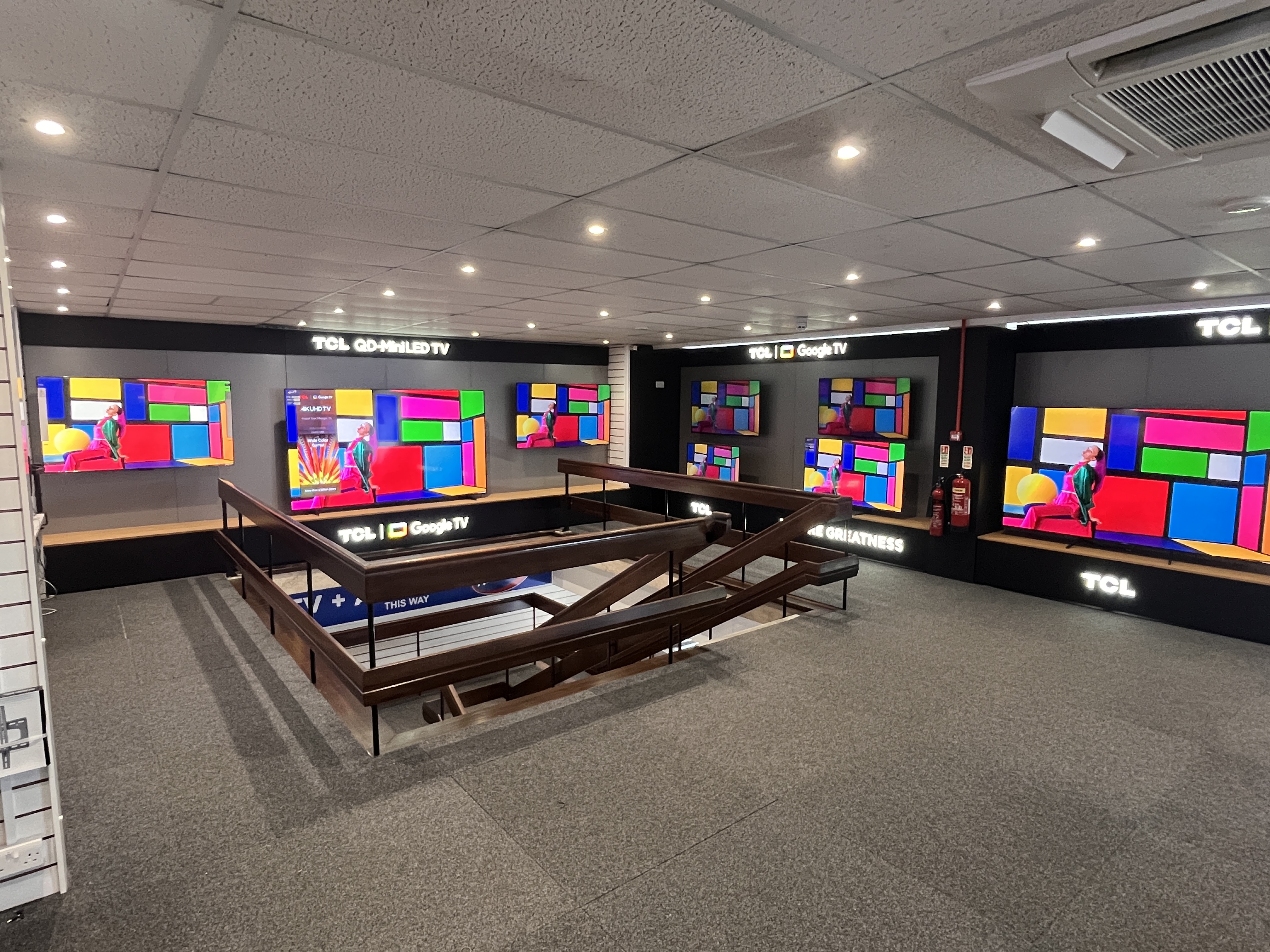TCL QD-Mini LED branded display unit at Cleverleys Blackpool — illuminated header panel and cable-managed screen plinth by Novus